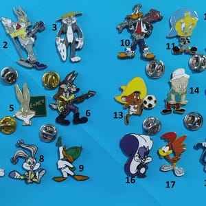 Peut inclure: Une collection de 18 épingles en émail colorées représentant divers personnages de dessins animés, notamment Bugs Bunny, Titi et Sylvester le chat. Les épingles sont numérotées de 1 à 18.