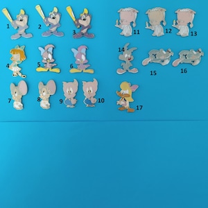 Peut inclure: Une collection de 17 épingles de personnages de dessins animés colorés. Les épingles représentent des personnages de la série de dessins animés Tiny Toon Adventures. Les épingles sont numérotées de 1 à 17.