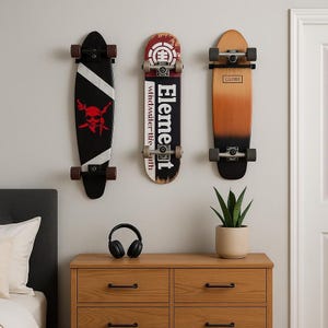 May include: Three skateboards mounted on a wall. One is black with a white stripe and a red skull graphic. The second is black with the word "Element" and a logo. The third is brown with the word "Globe".