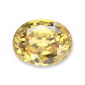 May include: A faceted oval-cut yellow gemstone with a brilliant, transparent appearance. The stone features a complex arrangement of geometric facets that reflect light, creating a bright, golden-yellow color throughout the entire surface.