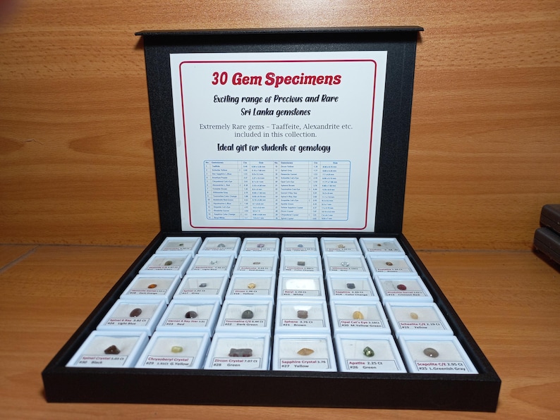 Może przedstawiać: Czarna gablota z 30 okazami kamieni szlachetnych. Gablota ma biały znak z czerwonym tekstem, kt&oacute;ry brzmi "30 Gem Specimens" i wymienia rzadkie kamienie szlachetne. Każdy kamień szlachetny jest prezentowany w małym, oznakowanym białym pudełku.