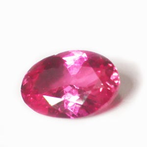 Peut inclure: Une pierre précieuse ovale de couleur rose vif avec des facettes.