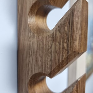 May include: A wooden wall-mounted rack with three curved hooks. The rack is made of dark brown wood with a natural grain pattern.