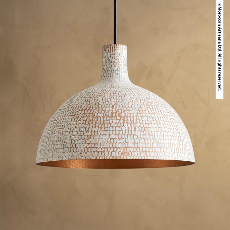 A white, textured lamp shade with a copper-colored interior is suspended from a ceiling.