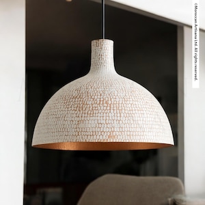 A modern, white pendant lamp with a textured finish hangs from the ceiling, casting a warm glow in the room.