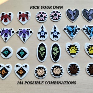 May include: A collection of various shaped jewelry components including hearts, diamonds, circles, ovals, and teardrops featuring colorful graphic designs of birds, turtles, roses, and paw prints with the text PICK YOUR OWN and 144 POSSIBLE COMBINATIONS.