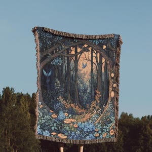 May include: A rectangular woven throw blanket featuring a detailed forest scene with dark blue and brown trees, orange and blue flowers, and two blue birds. The blanket has a fringed edge on the top and bottom and a circular frame design.