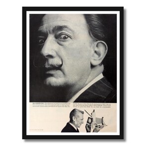 Op de afbeelding: Een zwart-witfoto van Salvador Dali, een beroemde kunstenaar, met een prominente snor. De tekst onder de afbeelding luidt "SALVADOR DALI. Deze ontwikkeling breidt zijn bruikbaarheid uit om een ​​tweede functie op te nemen.  Professionele handgreep. Let op de uitzonderlijke kwaliteit in detail en toon.  De kenmerken van de afdruk die is gemaakt met Kodaks nieuwe panchromatische film "Plus-X" worden in deze foto gedemonstreerd."