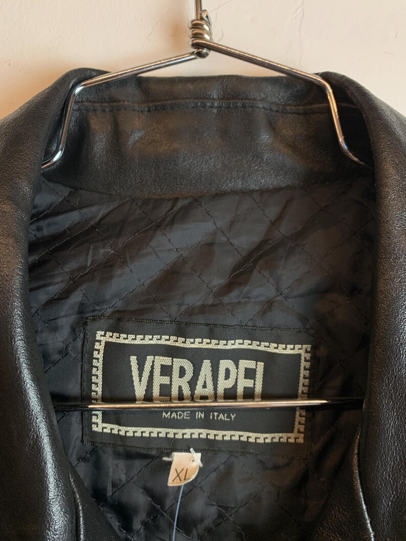 May include: Black leather jacket with a quilted lining. The label reads "VERAPEI MADE IN ITALY" and includes an XL size tag. The jacket is hanging on a metal hanger.