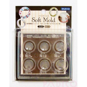 May include: A clear plastic mold with six round cavities for making rings. The mold is labeled "Soft Mold" and includes measurements for each cavity in millimeters. The mold is designed for use with resin or clay.