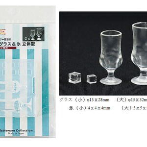 May include: A set of two clear glass miniature soda glasses and two ice cubes. The glasses are 1.1 inches (28 mm) tall and 0.5 inches (13 mm) in diameter. The ice cubes are 0.16 inches (4 mm) on each side. The larger glass is 1.3 inches (32 mm) tall and 0.6 inches (15 mm) in diameter. The larger ice cubes are 0.2 inches (5 mm) on each side.
