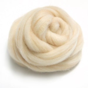 May include: A close-up of a large, fluffy ball of cream-colored wool roving.