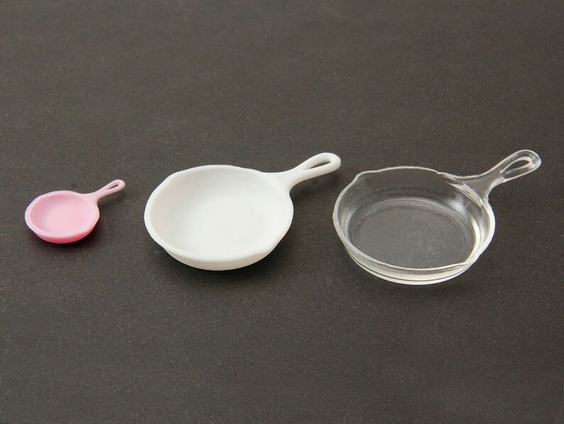 May include: Three miniature frying pans in different sizes and colors: pink, white, and clear.