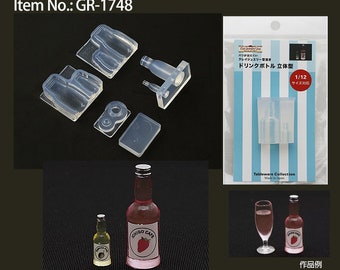 Peut inclure: Moules en plastique transparent pour des bouteilles miniatures, avec des exemples de bouteilles finies. L'image comprend un emballage avec un moule à bouteille et une bouteille finie. Le texte "ICHIGO CAFE" est visible sur les étiquettes des bouteilles. Réf. GR-1748.