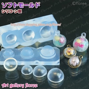 May include: A silicone mould for making round, dome-shaped resin ornaments. The mould has three large dome cavities and three smaller dome cavities. There are also three finished resin ornaments with floral designs inside.