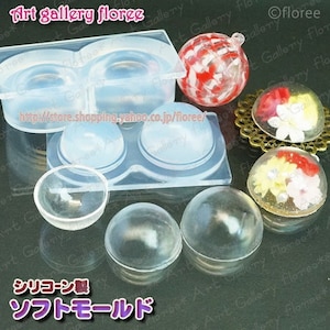 May include: A silicone mould for making round resin ornaments. The mould has two large round cavities and two smaller round cavities. There are also three finished resin ornaments, one with a red and white pattern, and two with floral designs.