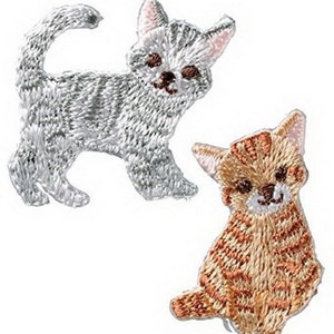 May include: Two embroidered iron-on patches of cats. One is a gray tabby cat with white markings. The other is an orange tabby cat with white markings.