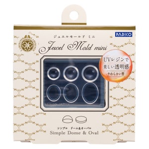 May include: A white box with gold accents featuring a set of Jewel Mold mini silicone molds for resin crafting. The molds are for creating dome and oval shapes. The box includes the text "Jewel Mold mini" and "Simple Dome & Oval".