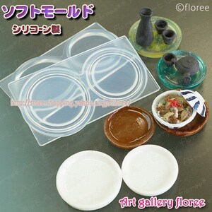 Puede incluir: Un molde de silicona transparente para hacer platos en miniatura. El molde tiene dos cavidades, cada una con forma circular. El molde se muestra con varios platos en miniatura hechos con el molde.