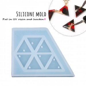 Puede incluir: Un molde de silicona transparente con seis cavidades en forma de triángulo. Cada cavidad tiene un pequeño círculo en el centro. El molde está diseñado para crear pendientes o colgantes de resina. El texto "SILICONE MOLD" y "Put in UV resin and harden" es visible en la imagen.
