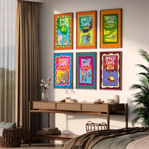 May include: A collection of six framed Roald Dahl book covers adorns a wall. The vibrant covers showcase illustrations and titles such as "BFG" and "The Twits." A wooden console table with decorative items is positioned beneath the framed books.