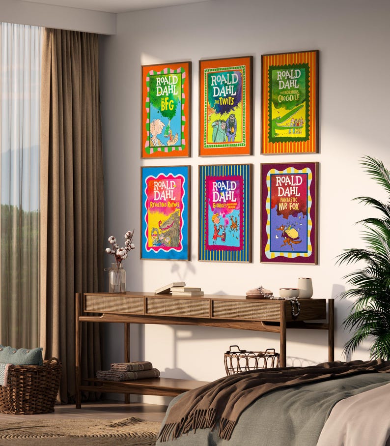May include: A collection of six framed Roald Dahl book covers adorns a wall. The vibrant covers showcase illustrations and titles such as "BFG" and "The Twits." A wooden console table with decorative items is positioned beneath the framed books.