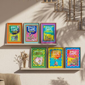 May include: A display of framed Roald Dahl book covers, such as "The Twits" and "Matilda." The colourful illustrations are presented on shelves against a neutral wall. The image includes a decorative birdcage and a staircase in the background, creating a warm atmosphere.