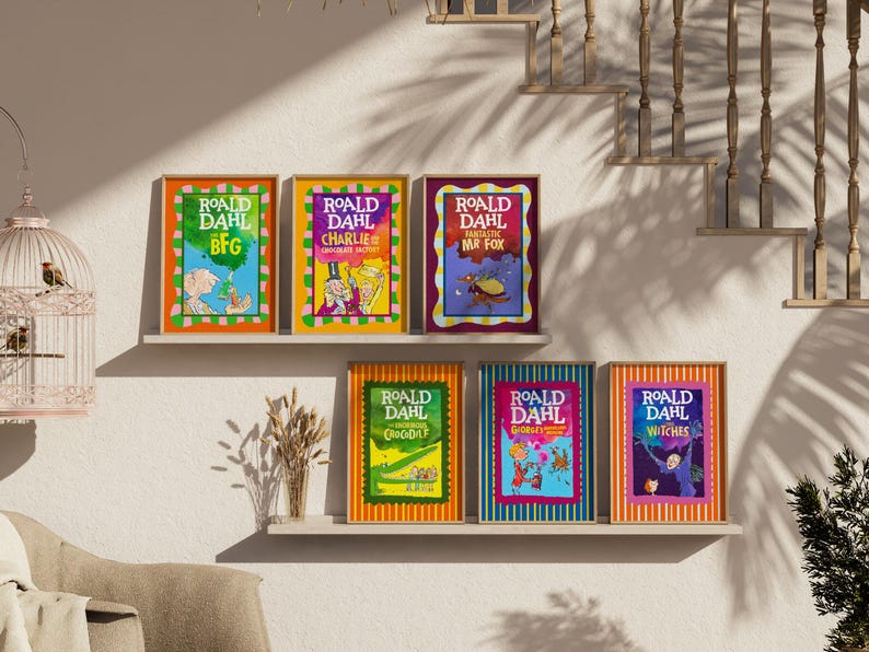 May include: A collection of six framed Roald Dahl book covers adorns a wall. The vibrant illustrations and titles, including "BFG" and "Charlie and the Chocolate Factory," are displayed in colorful frames. The arrangement creates a visually appealing display.