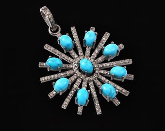 May include: A silver pendant with a sunburst design, featuring oval turquoise stones and small, sparkling diamonds. The pendant has a bail for a chain and is set against a black background.