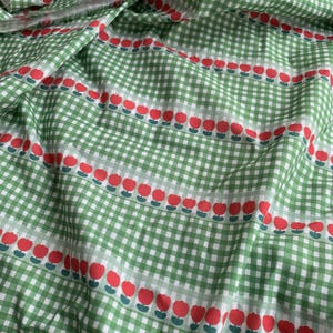 May include: A green and white gingham fabric featuring horizontal rows of small red tulip motifs with green stems. The pattern consists of a classic checkered grid background overlaid with repeating floral lines across the entire textile surface.