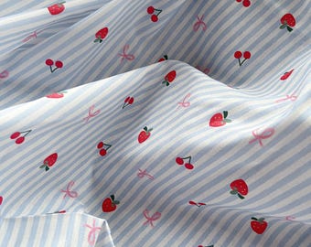 May include: Close-up of a fabric with a light blue and white striped pattern. The fabric is decorated with red strawberries, cherries, and pink bows. The fabric is folded, creating shadows and depth.
