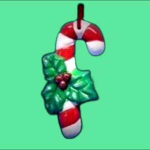 May include: A red and white candy cane Christmas ornament with a green holly leaf design.