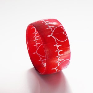 May include: Red silicone bracelet with a white EKG pattern and heart designs.