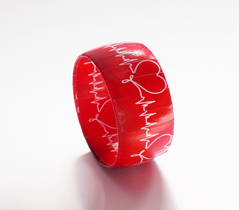 May include: Red silicone bracelet with a white EKG pattern and heart designs.