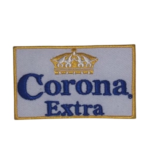 Peut inclure: Un patch brodé blanc avec une couronne dorée et le texte "Corona Extra" en bleu.