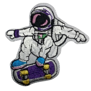 Puede incluir: Un parche bordado de un astronauta con un traje espacial blanco y un casco morado, haciendo skateboard en una tabla de skate morada y amarilla.