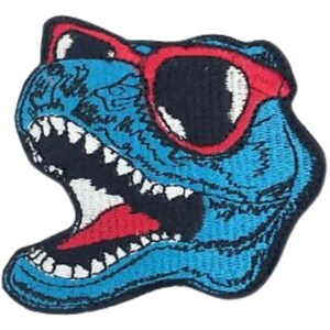 Può includere: Testa di dinosauro blu con un ghigno pieno di denti che indossa occhiali da sole rossi. Gli occhi del dinosauro sono neri e gli occhiali da sole hanno una montatura rossa.
