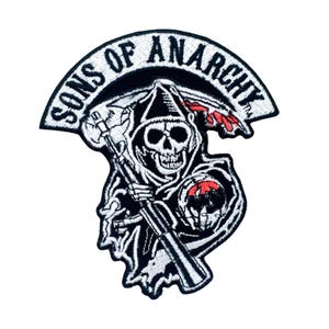 Op de afbeelding: Geborduurde patch met de woorden "SONS OF ANARCHY" in witte gebogen tekst boven een zwart-wit figuur van de Grim Reaper met een zeis en een schedel. De reaper heeft een zwarte kap en rode accenten.