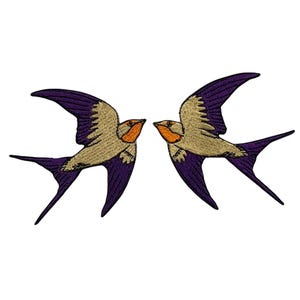 May include: Two embroidered swallow bird patches in purple and beige. The birds are facing each other with their wings outstretched.