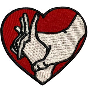 May include: Red heart-shaped embroidered patch with a white hand making a heart shape with its fingers.