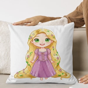 Peut inclure: Un coussin blanc avec une illustration de dessin anim&eacute; d'une fille aux longs cheveux blonds, portant une robe violette et une couronne de fleurs. La fille a les yeux verts et un grand sourire.