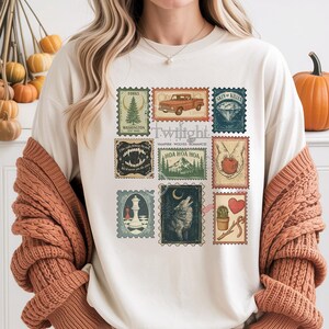 Vintage Twilight stamp shirt featuring retro postage-style graphics inspired by the Twilight saga, including Forks Washington, classic red truck, vampire fangs, wolves, apple, and chess piece. Printed on premium Comfort Colors or Gildan cotton tee for a soft and durable fit. Perfect gift for Twilight fans, book lovers, or movie marathon nights. Cozy fan apparel with aesthetic retro vibes, ideal for everyday casual wear or as a unique fandom collectible shirt.