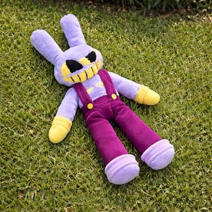 May include: A plush toy rabbit with a menacing expression, lying on green grass. The rabbit is primarily purple, with yellow hands and feet, and wears purple overalls. Its face features black eyes and a yellow, toothy grin.
