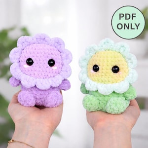 May include: Two plush, crocheted sunflower dolls. One is lavender with a light purple petal design, the other is green with a yellow center and light green petals. Both have black eyes and smiling faces. The image includes a green circle with the text "PDF ONLY".