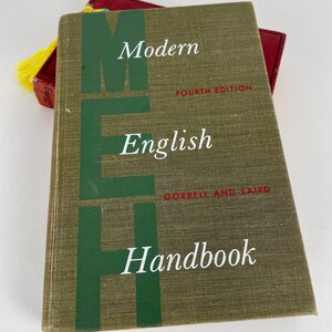 May include: A hardcover book titled "Modern English Handbook" with a green cover and white text. The book is a fourth edition by Gorrell and Laird. A red book with a yellow tassel is partially visible.
