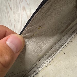 May include: Close-up of the inside of a black shoe. The interior is light beige leather with a stitched seam along the edge. The number "45" is stamped in gold near the heel.