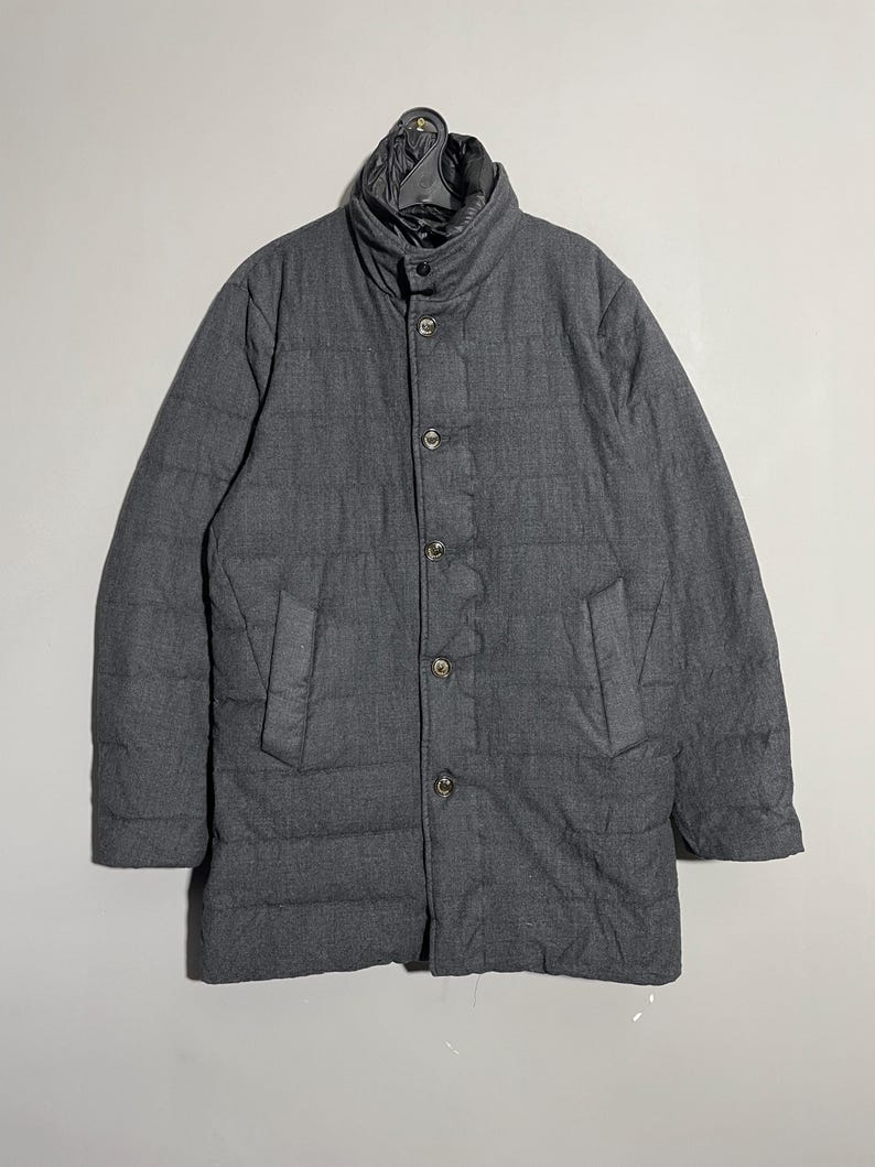 May include: A gray quilted puffer jacket with a button closure and a stand-up collar.