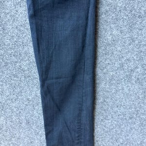 Op de afbeelding: Een enkele broekspijp gemaakt van donker antracietgrijze denimstof. Het materiaal heeft een zichtbare keperbinding en een recht model. Het kledingstuk is van bovenaf gefotografeerd, waardoor de lengte en de textuur van de stof zichtbaar zijn.