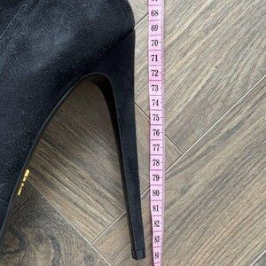 May include: A black suede high-heeled shoe with a stiletto heel. A pink measuring tape shows the heel height is approximately 3.3 inches. The shoe has a pointed toe and a sleek, elegant design.