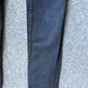 Op de afbeelding: Een donkergrijze spijkerbroek van denim met een klassieke vijf-pocket constructie en zichtbare verticale stiksels langs de buitenste broekspijpen. De stof heeft een subtiele, uniforme textuur die kenmerkend is voor katoenen denim met een vervaagde antracietkleurige afwerking.